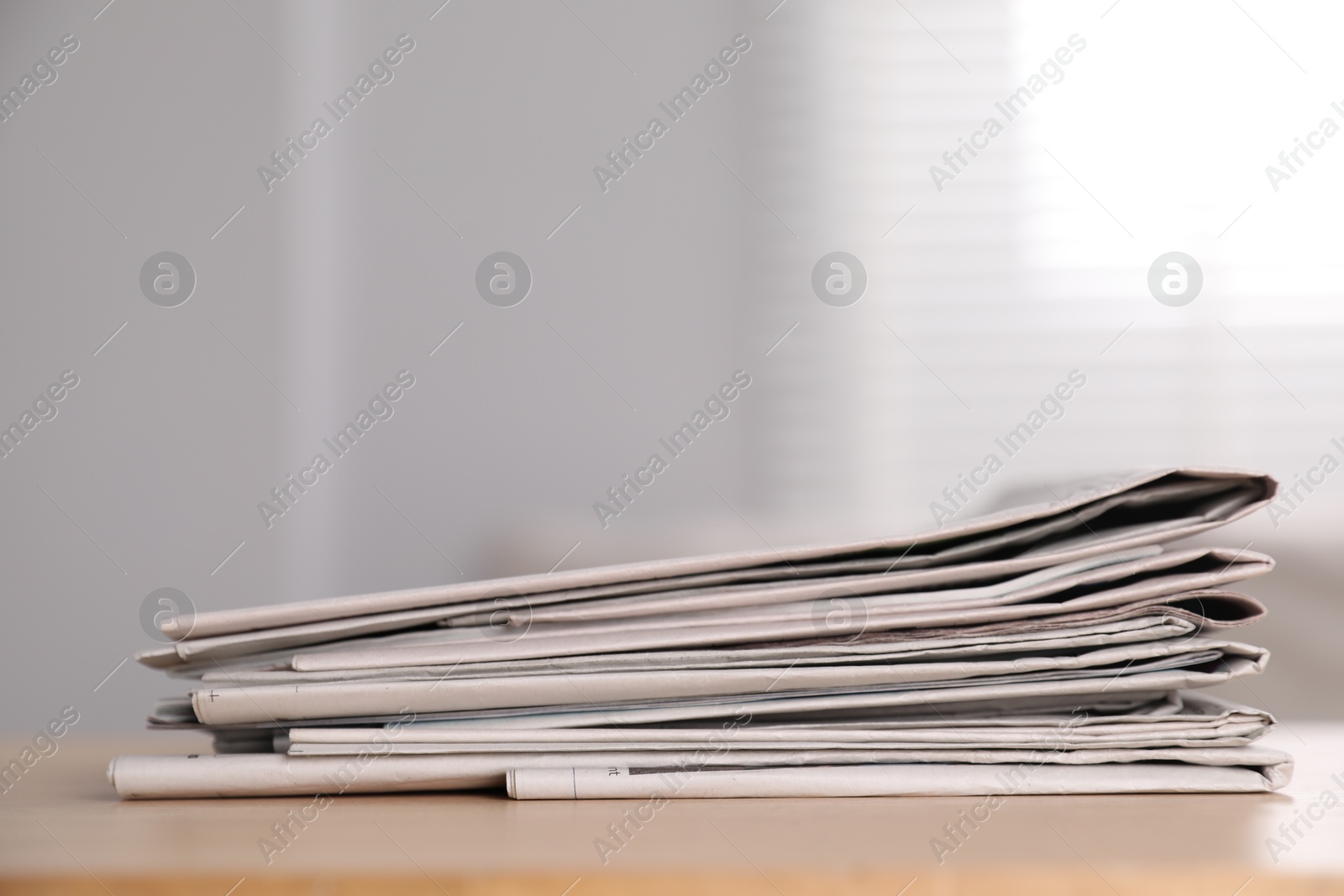 Photo of Stack of newspapers in different languages on table indoors. Space for text