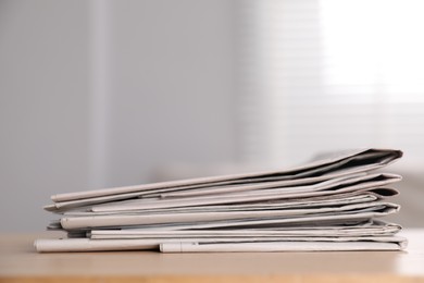 Stack of newspapers in different languages on table indoors. Space for text