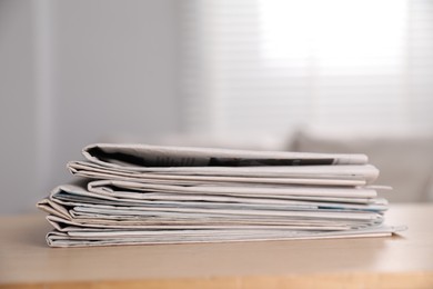 Stack of newspapers in different languages on table indoors