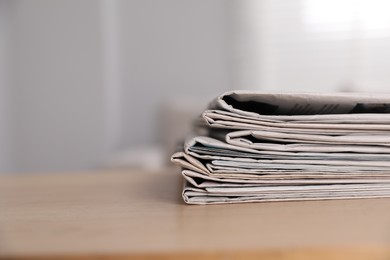 Stack of newspapers in different languages on table indoors. Space for text