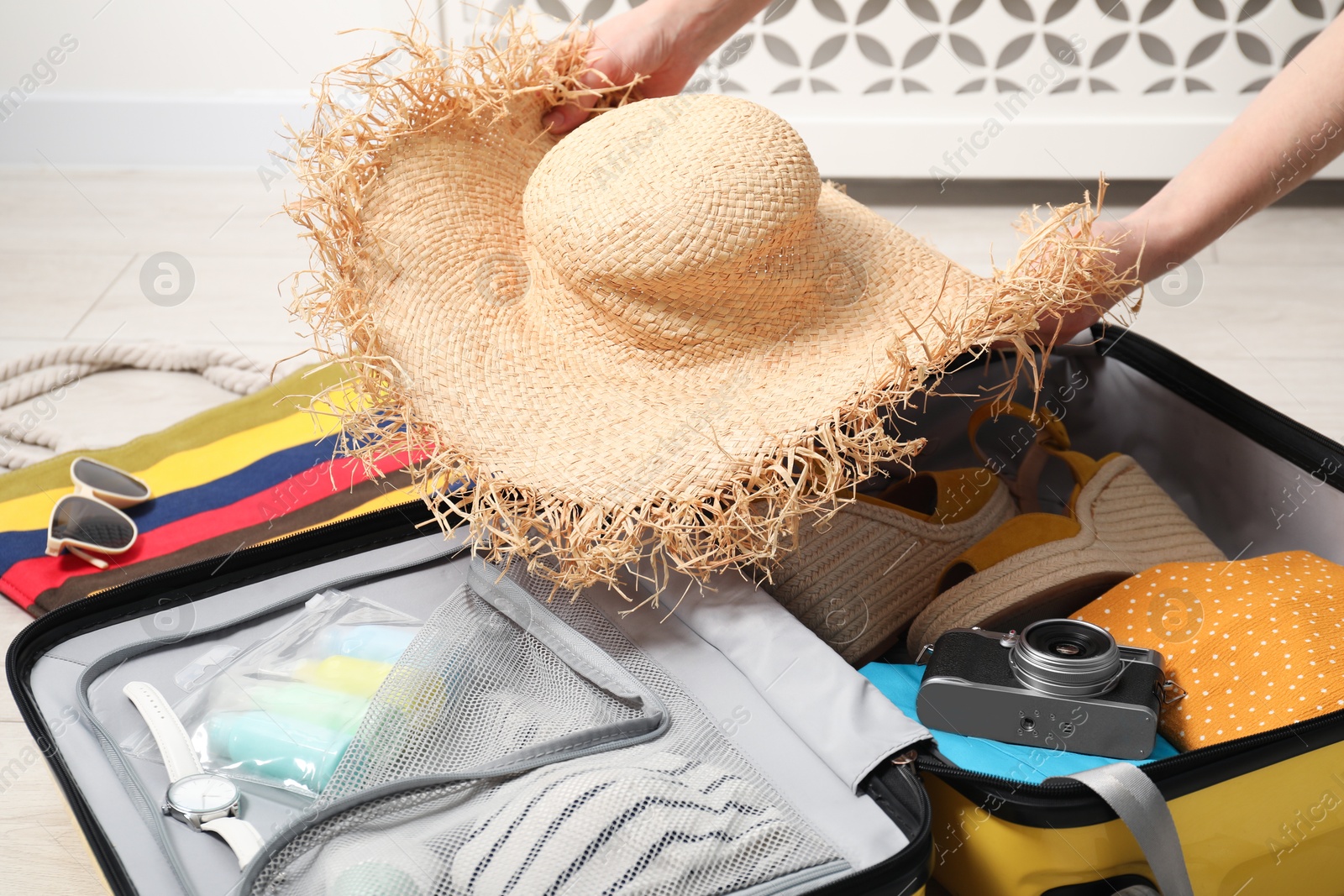 Photo of Woman packing suitcase for trip at home, closeup