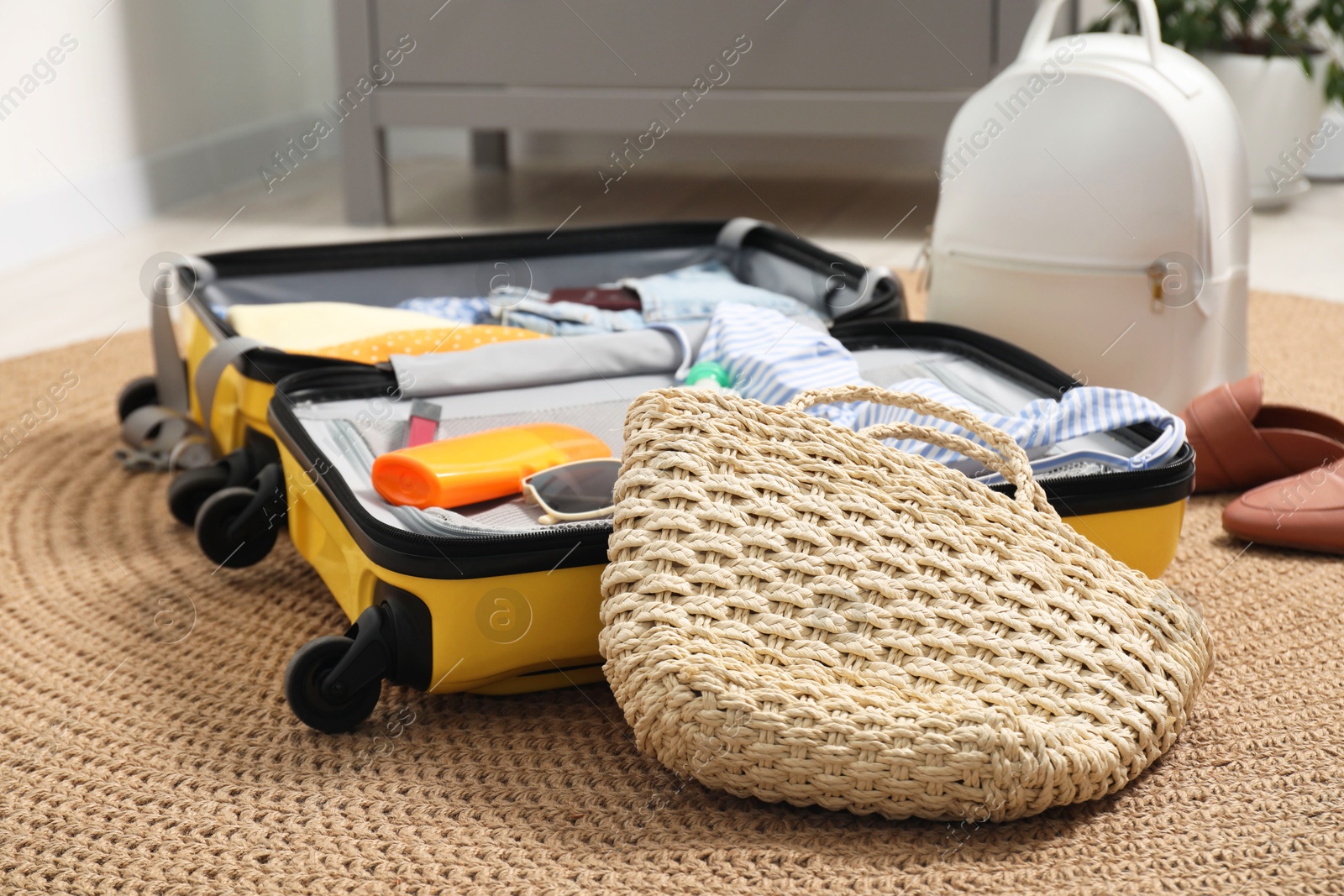 Photo of Open suitcase with traveler's belongings on rug, closeup