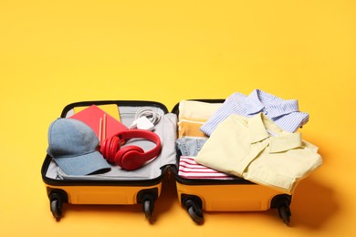 Photo of Open suitcase with traveler's belongings on yellow background