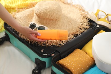 Woman packing suitcase for trip in bedroom, closeup