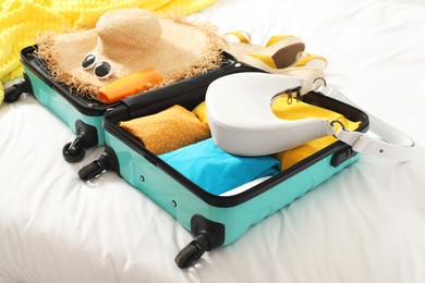 Photo of Open suitcase with traveler's belongings on bed, closeup