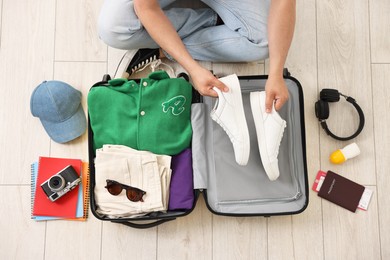 Man packing suitcase on floor at home, top view