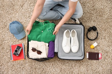 Man packing suitcase on floor at home, top view