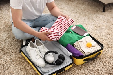 Man packing suitcase on floor at home, closeup