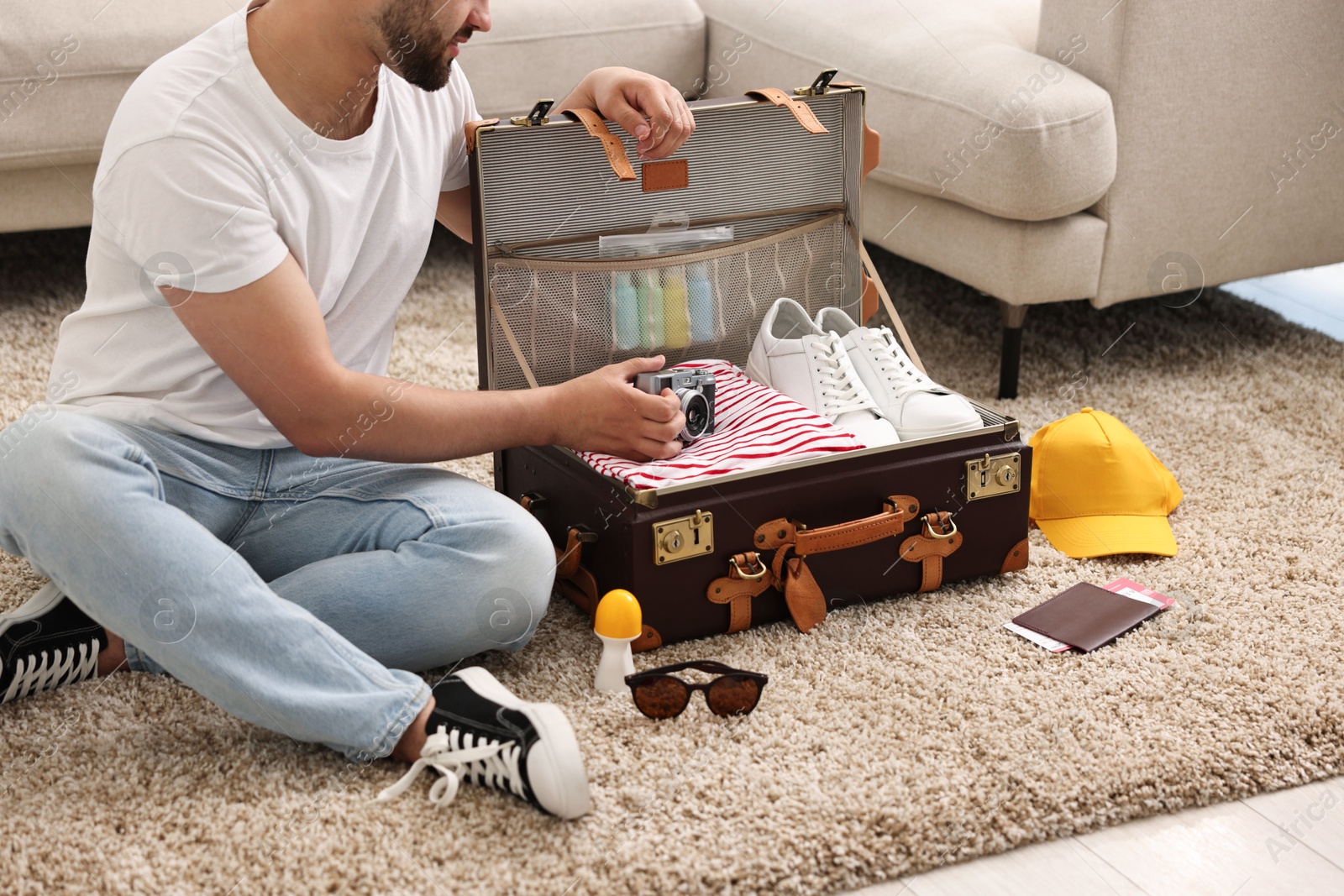 Photo of Man packing suitcase on floor at home, closeup