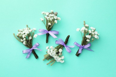 Many stylish boutonnieres on turquoise background, flat lay