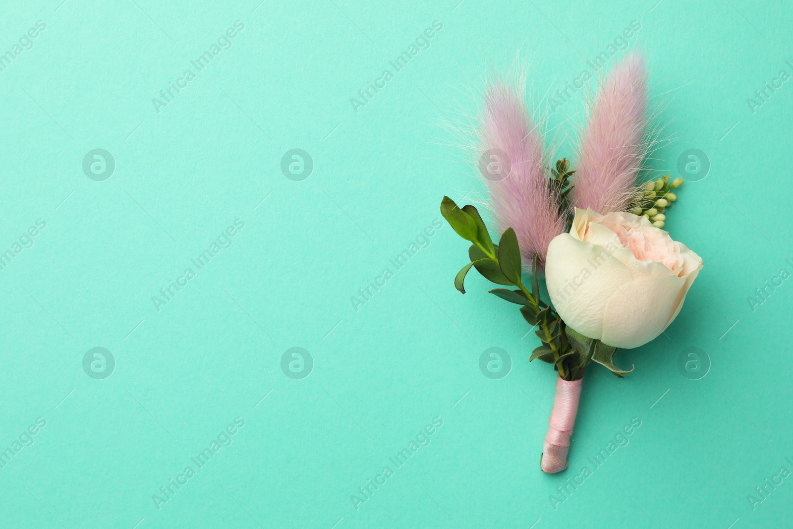 Photo of Small stylish boutonniere on turquoise background, top view. Space for text