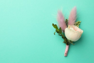 Small stylish boutonniere on turquoise background, top view. Space for text