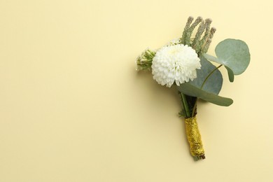 Small stylish boutonniere on beige background, top view. Space for text