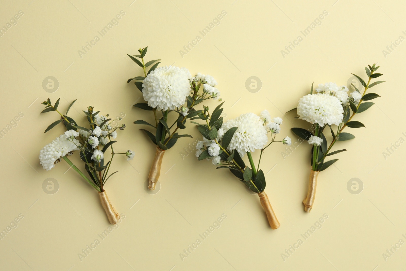 Photo of Many stylish boutonnieres on beige background, flat lay