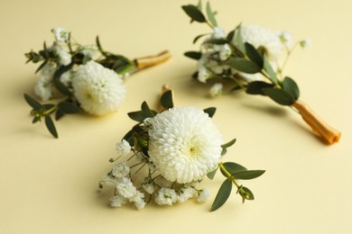 Photo of Many stylish boutonnieres on beige background, closeup