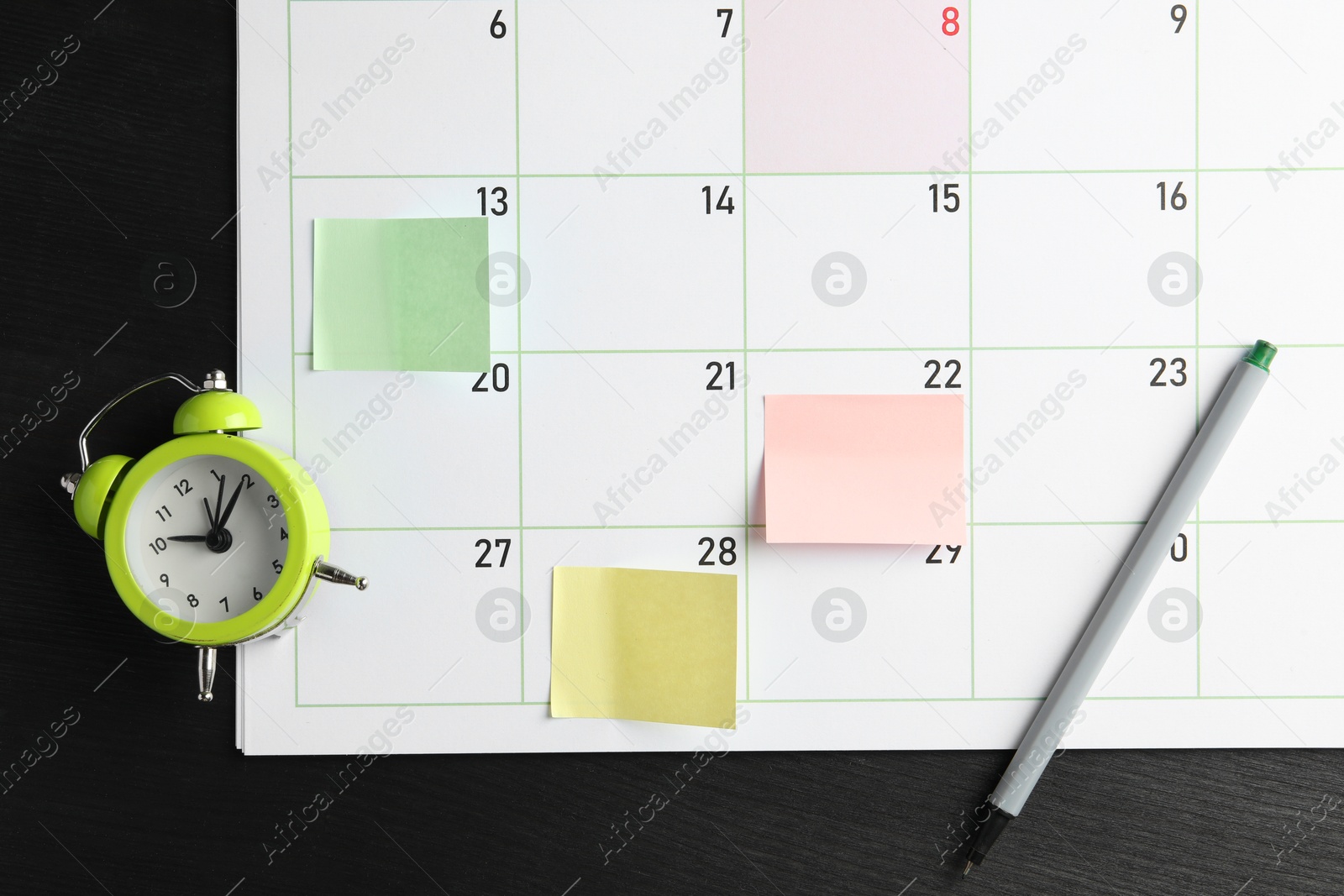 Photo of Timetable. Planner with sticky notes, pen and alarm clock on black wooden table, top view