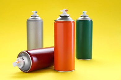 Photo of Many spray paint cans on yellow background