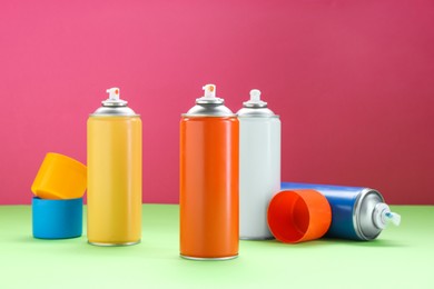 Many spray paint cans on color background