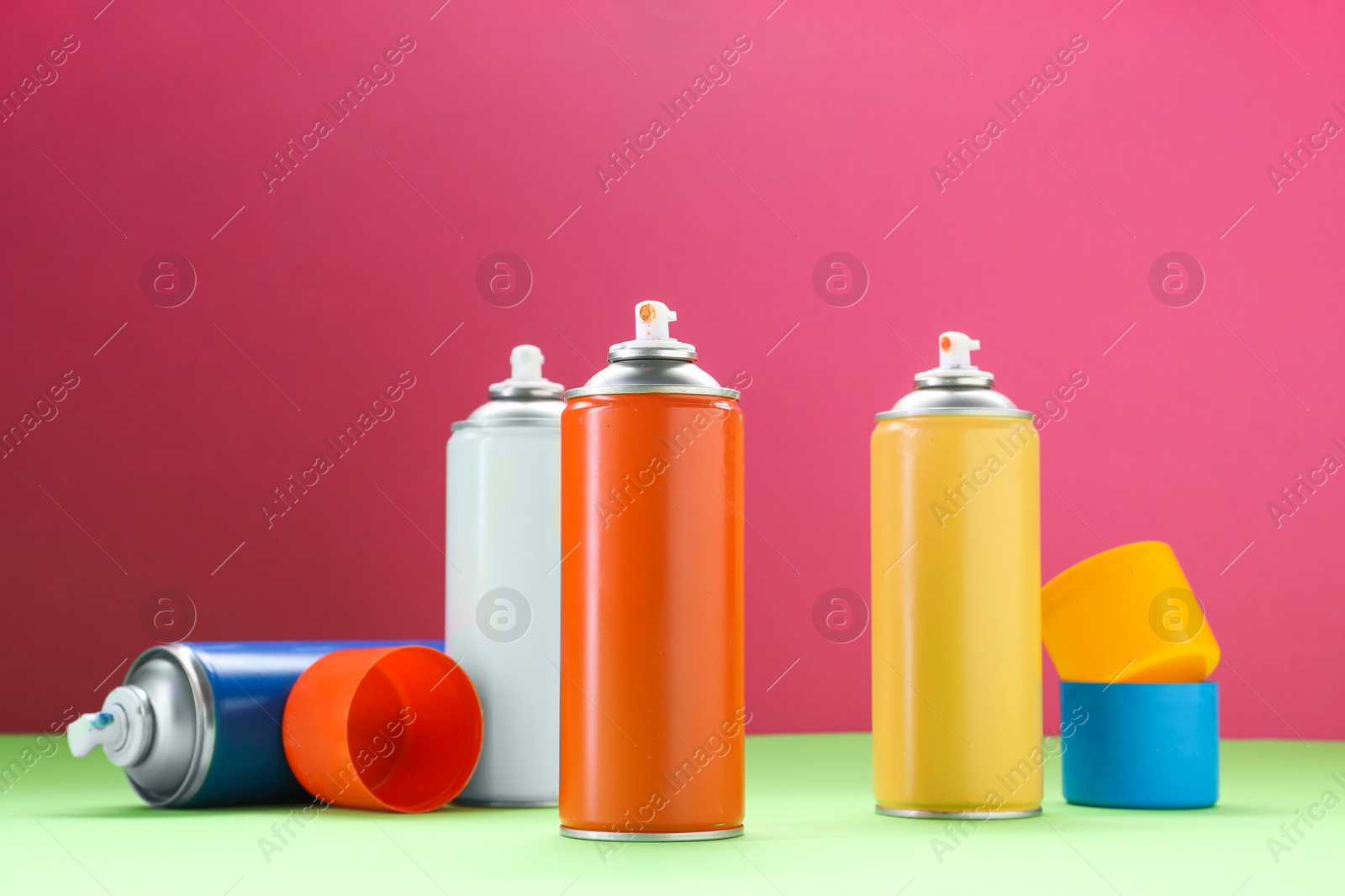 Photo of Many spray paint cans on color background