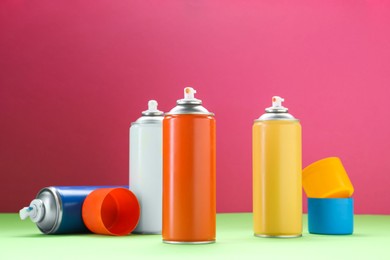 Many spray paint cans on color background