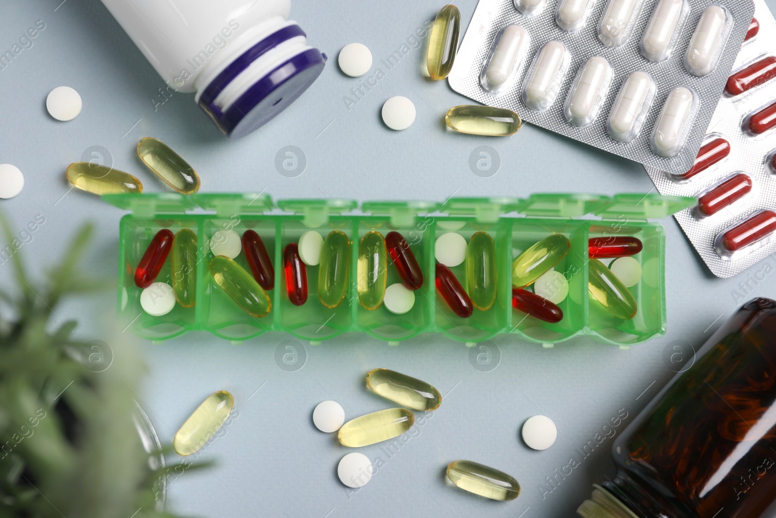 Photo of Different pills, organizer and medical jars on light background, flat lay