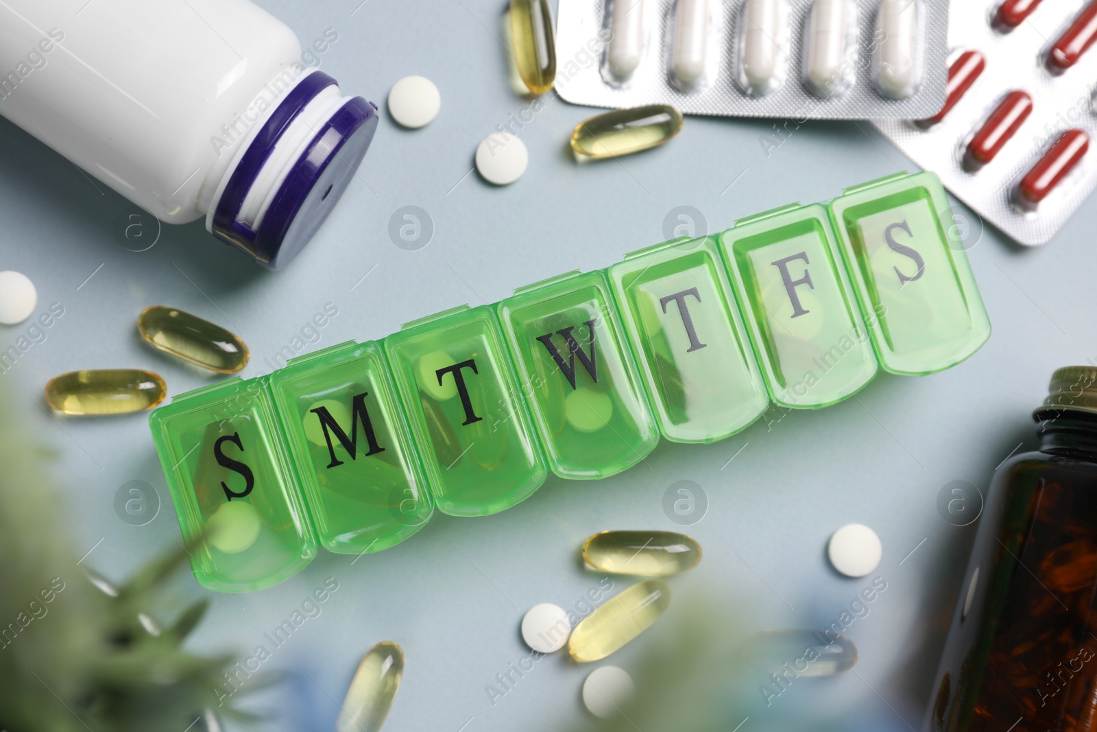 Photo of Different pills, organizer and medical jars on light background, flat lay