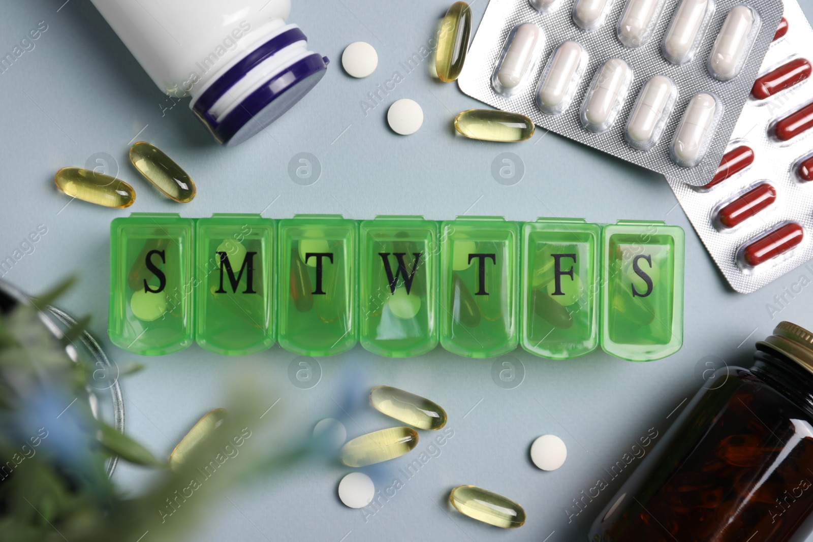 Photo of Different pills, organizer and medical jars on light background, flat lay