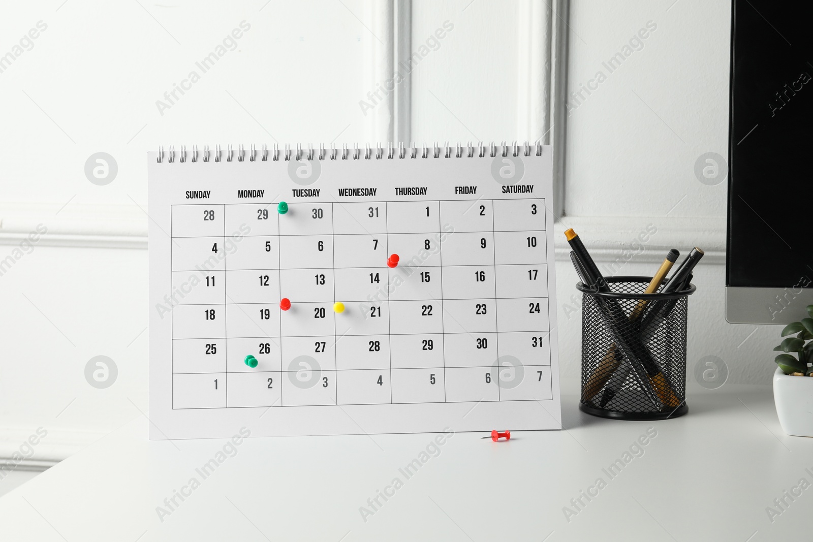 Photo of Timetable. Calendar with drawing pins and stationery on white table indoors