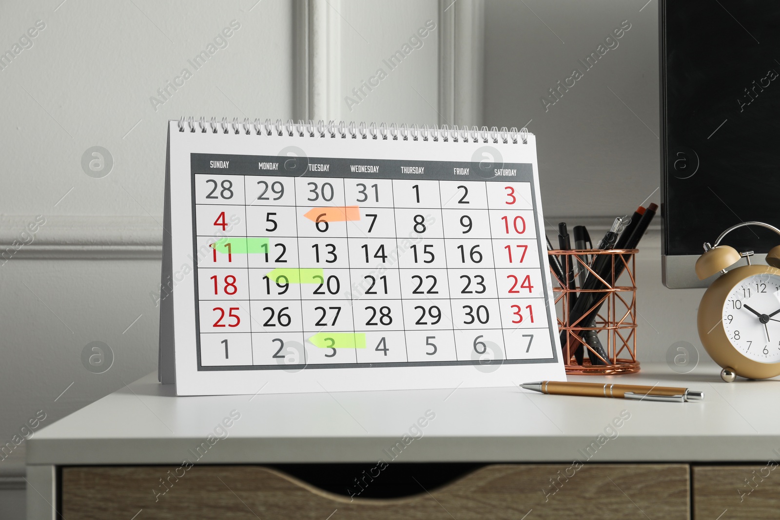 Photo of Timetable. Calendar with marked dates, alarm clock and stationery on white table indoors