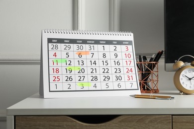 Timetable. Calendar with marked dates, alarm clock and stationery on white table indoors