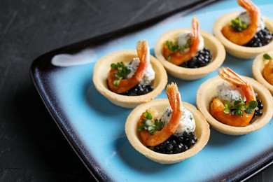 Delicious canapes with shrimps and black caviar on black table, closeup