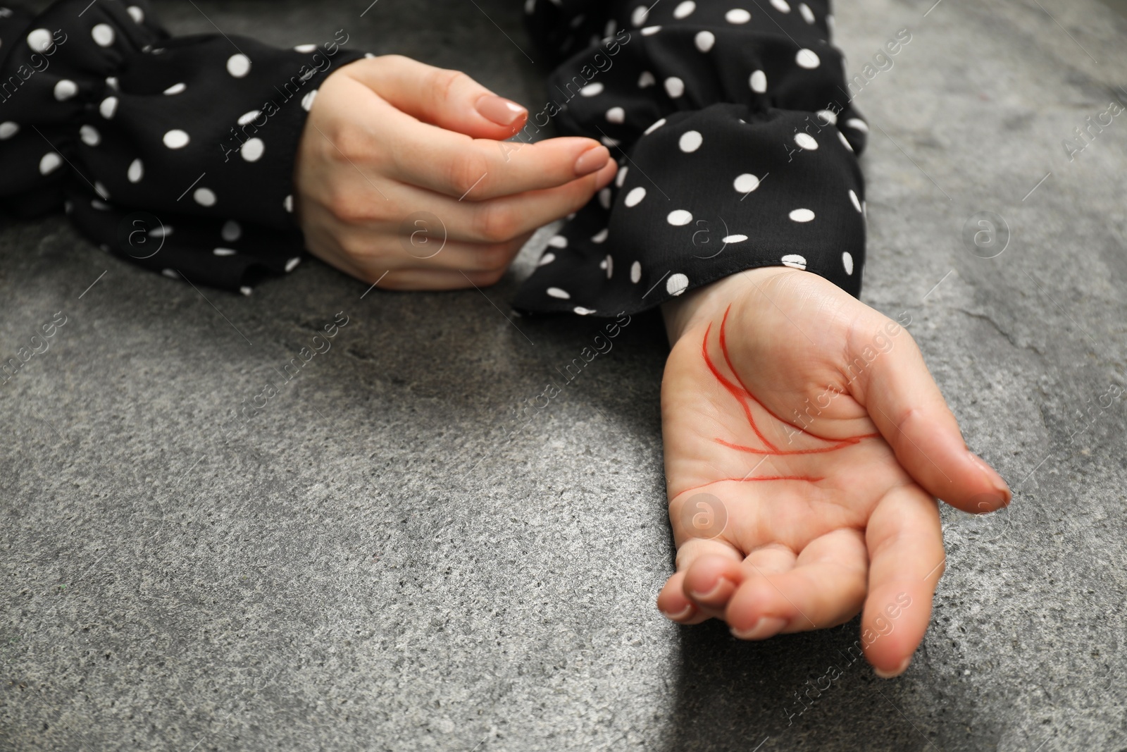 Photo of Woman showing palm with drawn lines at grey table, closeup. Chiromancy and foretelling