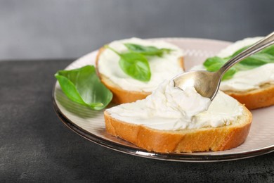 Photo of Delicious sandwiches with cream cheese and basil leaves on grey table, closeup