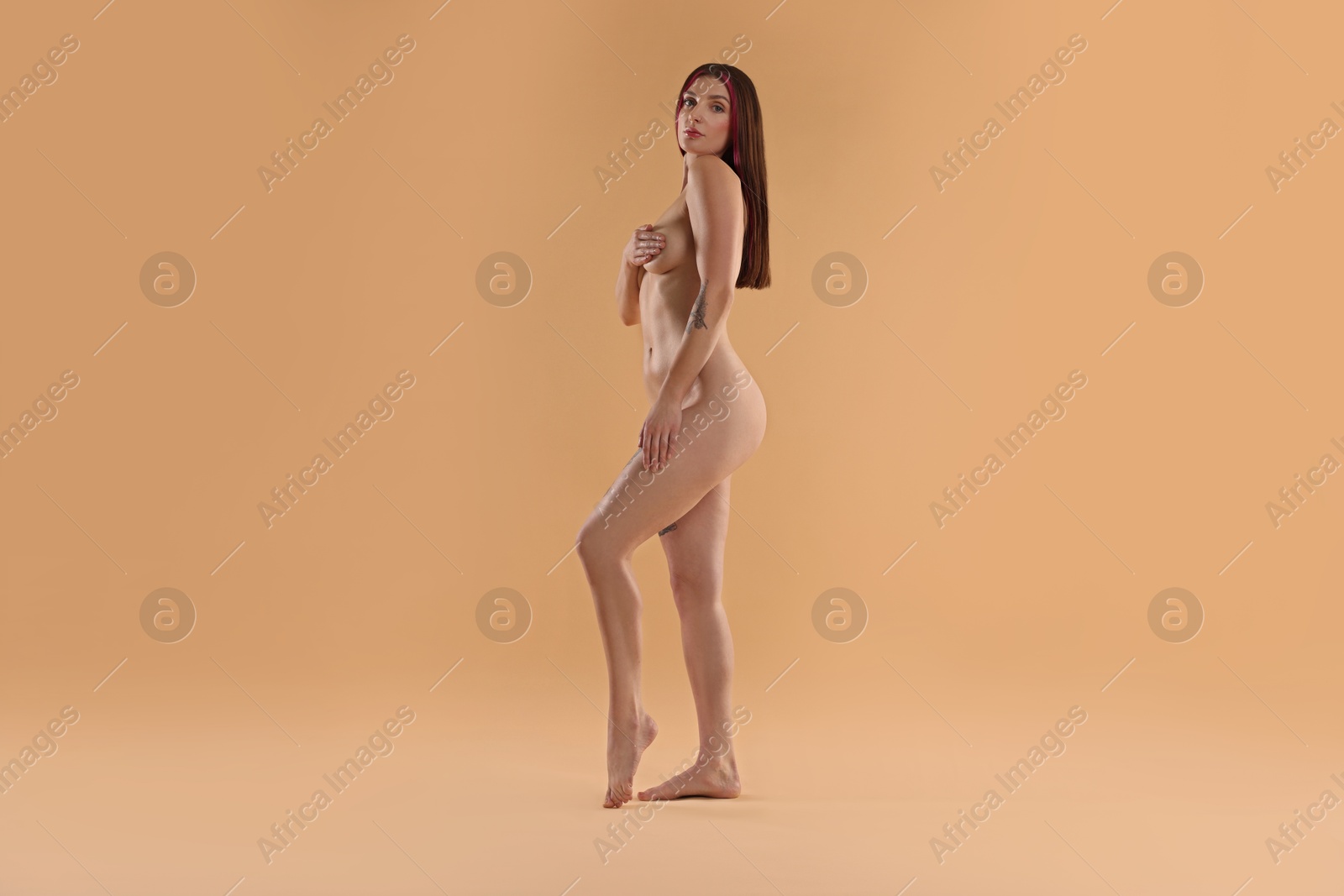 Photo of Full length portrait of sexy nude woman on beige background