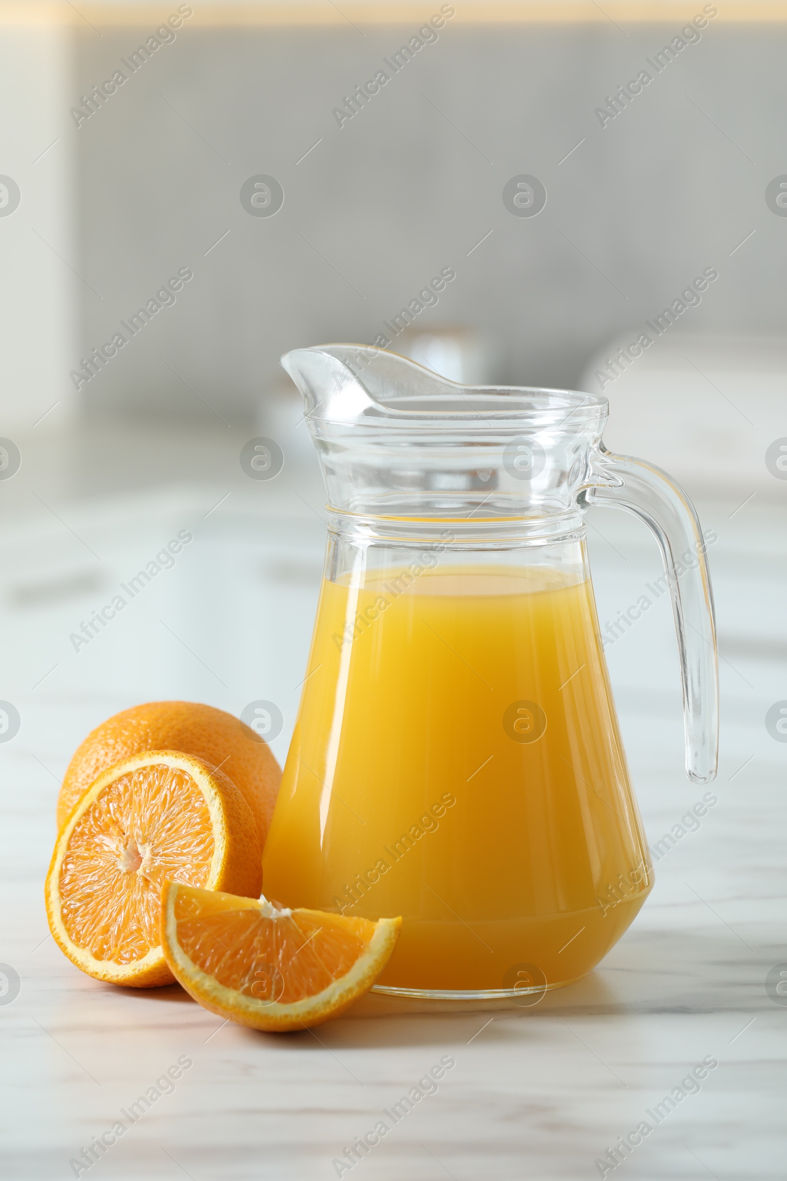 Photo of Tasty orange juice in jug and citrus fruits on white marble table