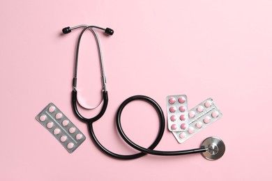 Photo of Stethoscope and pills on pink background, flat lay