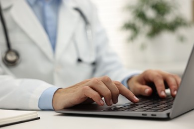 Photo of Doctor using laptop at white table in hospital, closeup