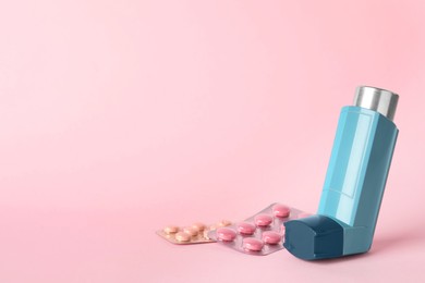 Photo of Inhaler and pills on pink background, closeup with space for text. Asthma treatment