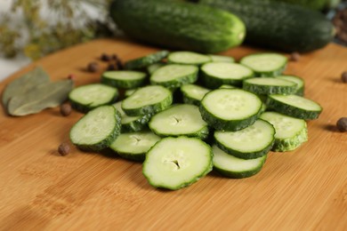 Photo of Board with fresh cucumbers and spices on table, closeup