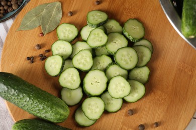 Board with fresh cucumbers and spices on table, top view