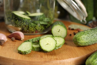 Board with fresh cucumbers and spices on table, closeup