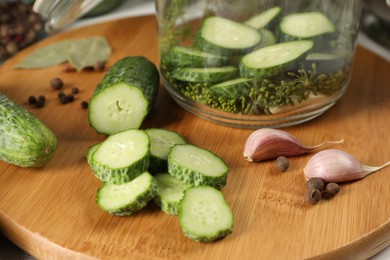 Board with fresh cucumbers and spices on table, closeup