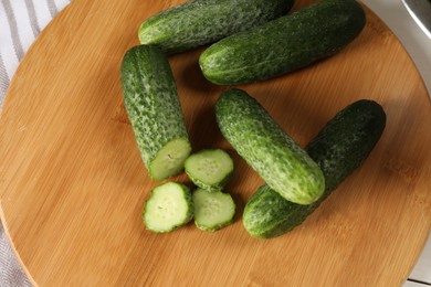 Board with fresh cucumbers on table, top view