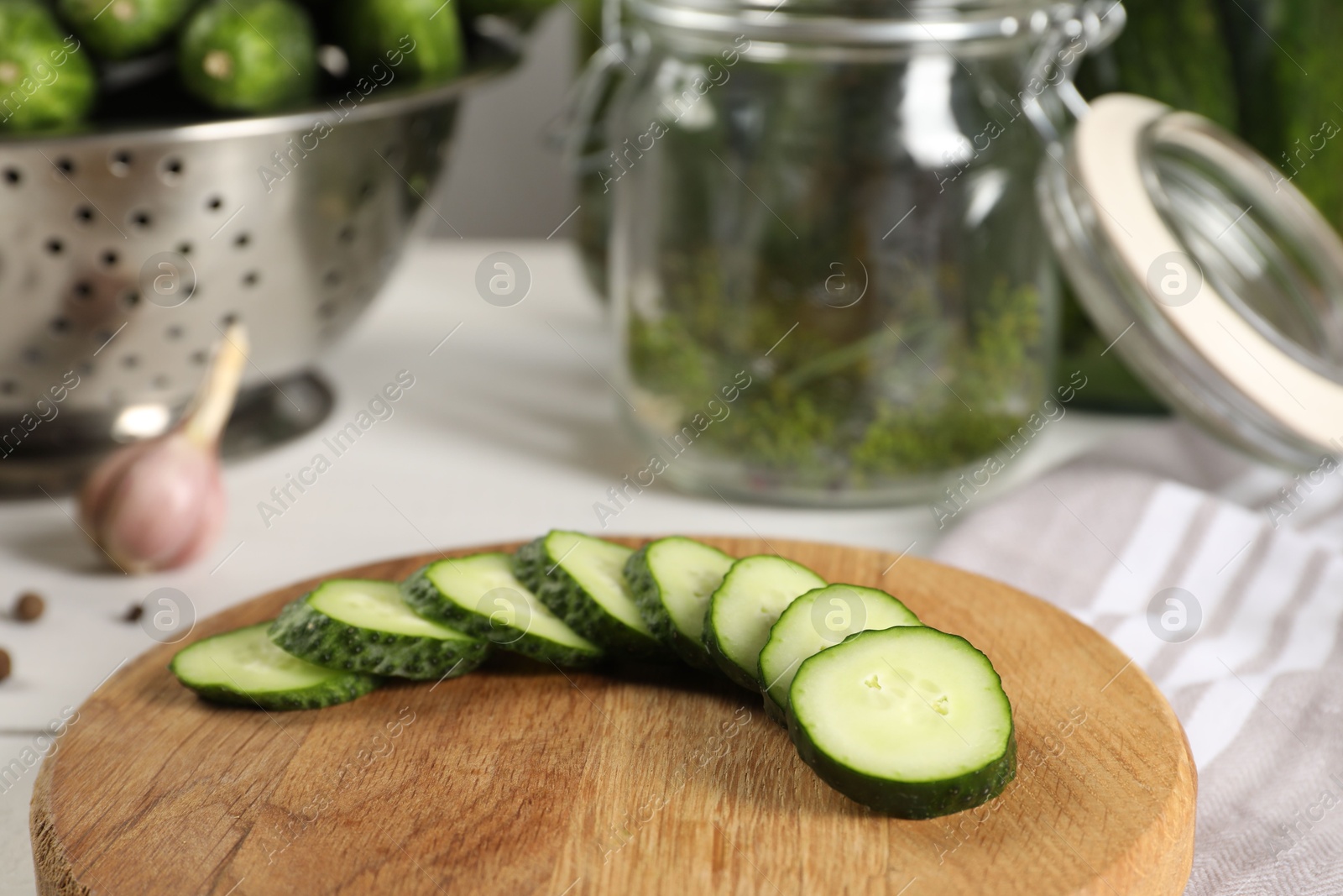 Photo of Board with fresh cut cucumber on light table, closeup