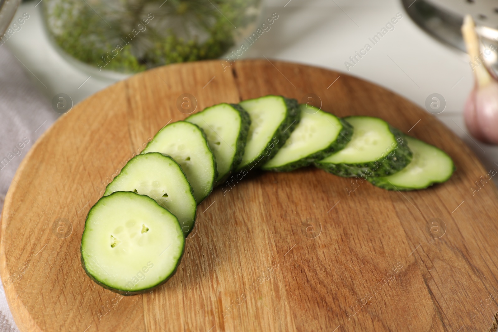 Photo of Board with fresh cut cucumber on light table, closeup