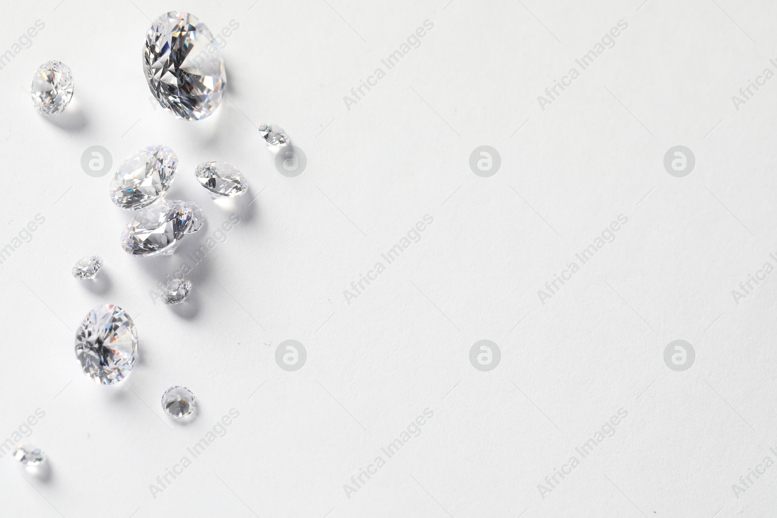 Photo of Many beautiful shiny diamonds on white background, flat lay. Space for text