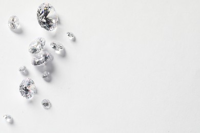 Photo of Many beautiful shiny diamonds on white background, flat lay. Space for text