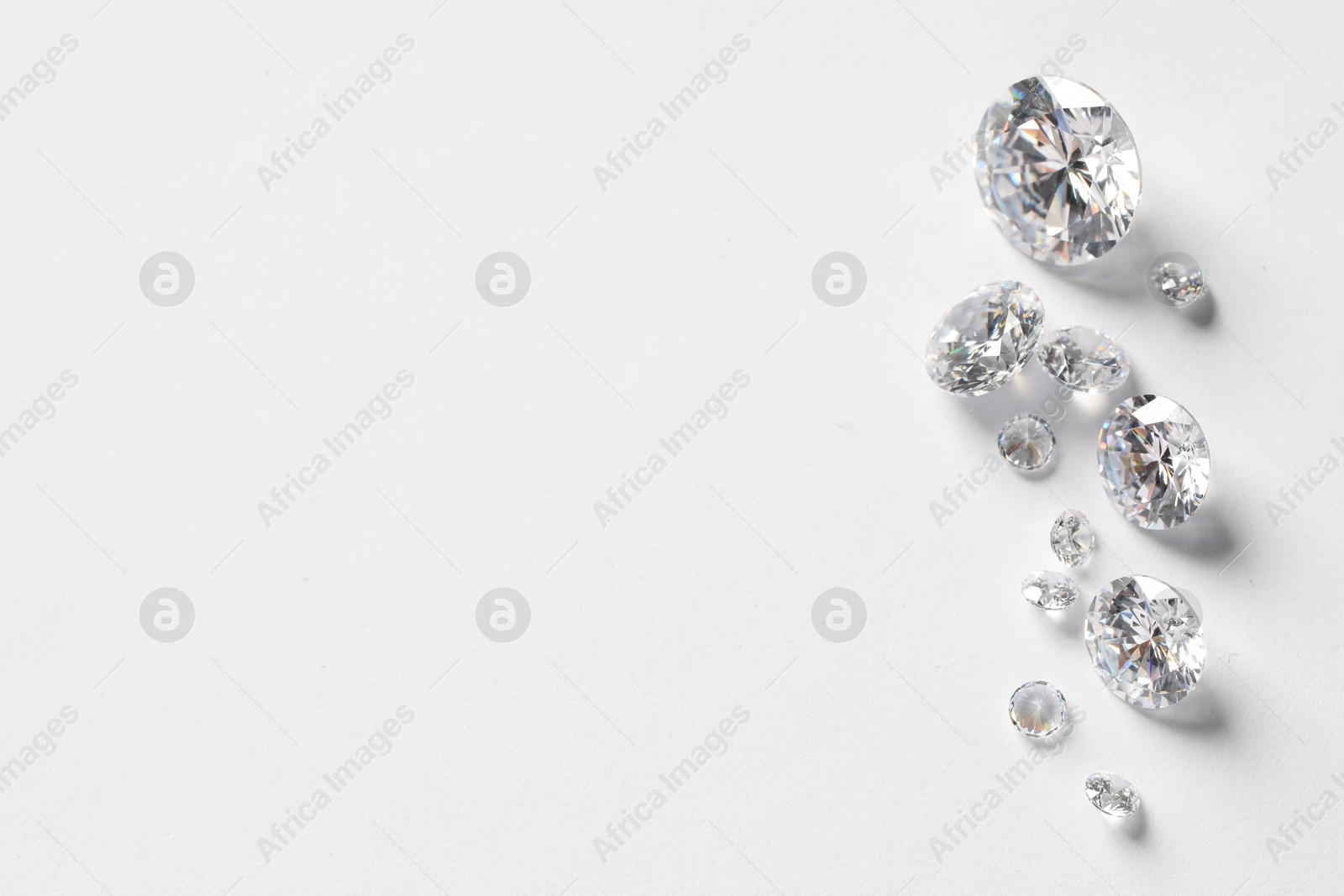 Photo of Many beautiful shiny diamonds on white background, flat lay. Space for text