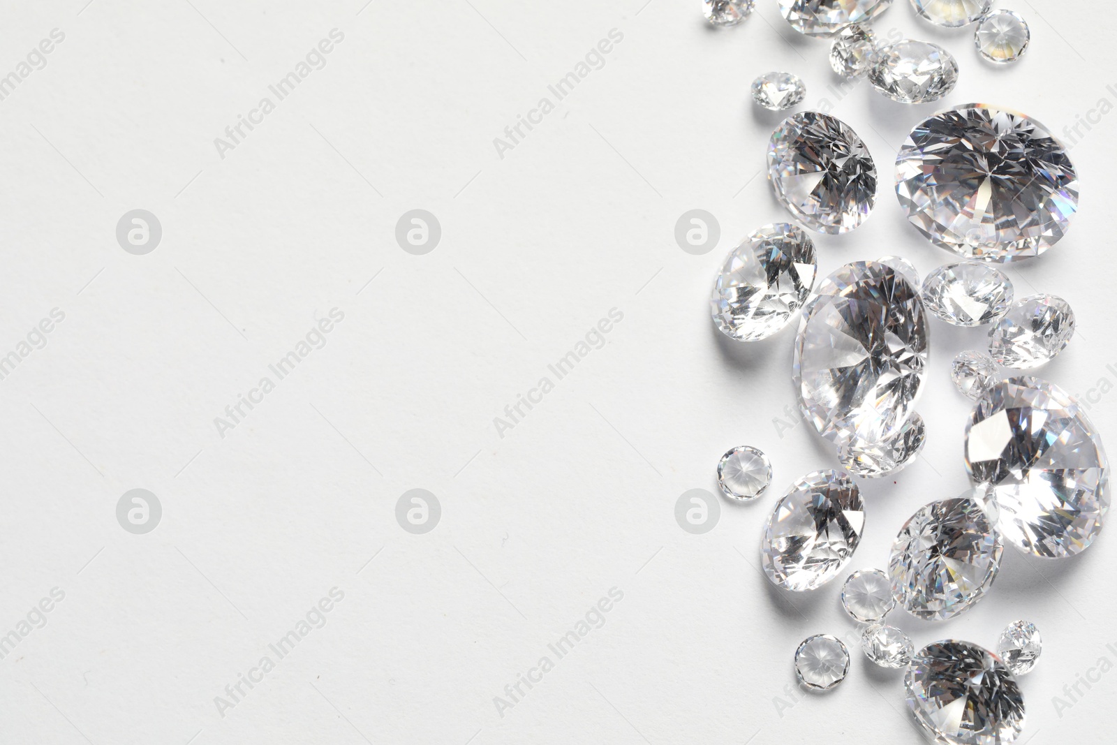 Photo of Many beautiful shiny diamonds on white background, flat lay. Space for text