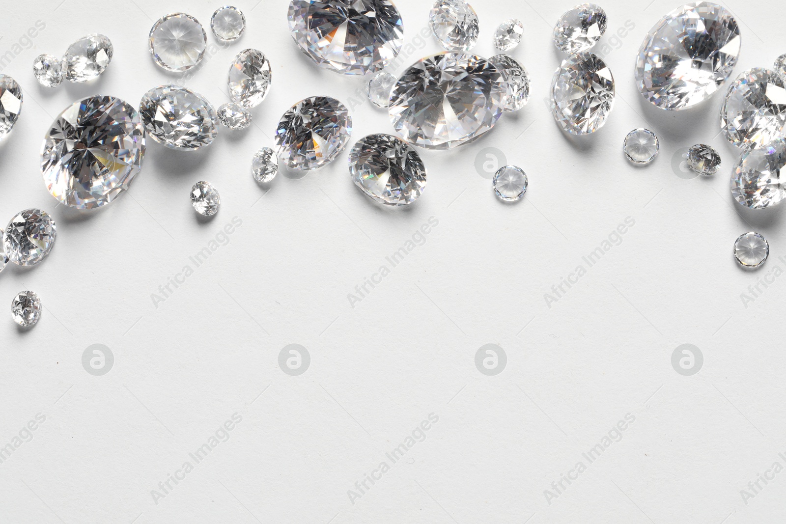 Photo of Many beautiful shiny diamonds on white background, flat lay. Space for text